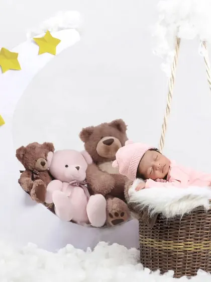 A dreamy moon and stars theme, with a baby sleeping in a basket next to a crescent moon filled with teddy bears.