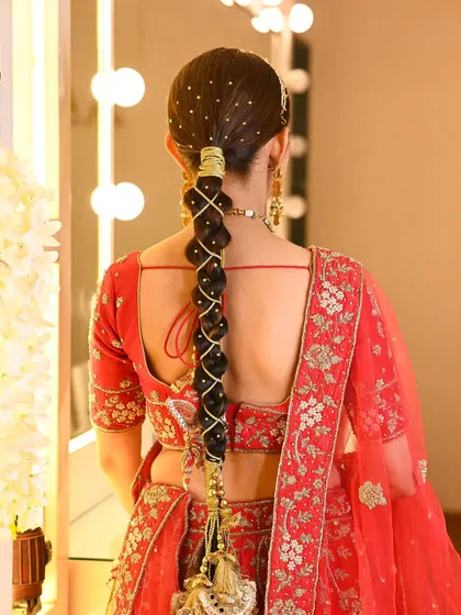 A classic bridal look featuring a long, traditional Punjabi braid. I wove golden threads and accessories through the parandi to complement the bride's red lehenga, creating a regal and authentic wedding hairstyle.