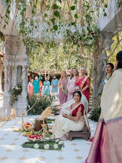 A bride awaits the start of her ceremony in our 'Love in Ruins' mandap. The design, featuring ancient-style stone pillars and organic floral growth, was created to feel timeless and seamlessly integrated with the venue's natural beauty.