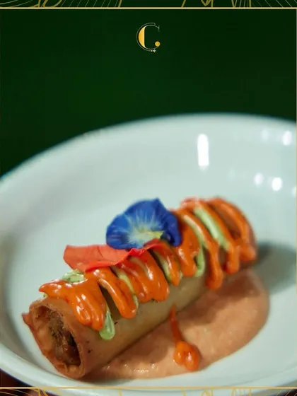 A close-up of our Thai Cigar Roll, artfully drizzled with two types of sauce and garnished with an edible flower. This is an example of how we turn a simple snack into a piece of culinary art.
