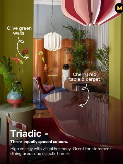 A triadic color scheme uses three equally spaced colors on the wheel, like the olive green, cherry red, and blue in this room. It creates high energy with visual harmony, great for statement dining areas.