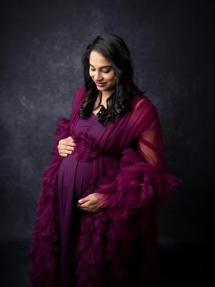 A serene solo portrait of an expecting mother cradling her bump. The soft lighting and her gentle expression create a peaceful and beautiful image.