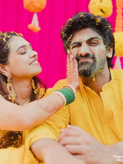 A playful moment during the Haldi ceremony, as the bride gently applies turmeric to the groom's face.