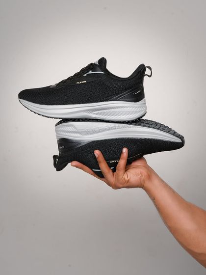 A hand-held shot that gives a sense of scale and detail for these black running shoes. It's a simple yet effective way to highlight the product's design.