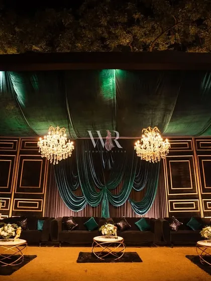 I create luxurious lounge spaces that invite guests to relax in style. This setup, themed 'Velvet Nights & Gilded Dreams', featured plush teal velvet sofas against a custom gold-framed backdrop, turning a simple corner into a chic and opulent retreat.