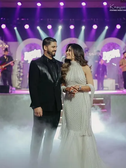 The couple shares a look of love on the smoke-filled stage, with the live band in the background. A perfect candid moment from their reception night.