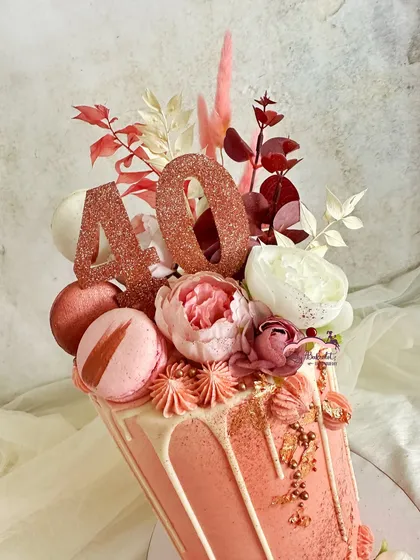 A close-up of the ruby anniversary cake, showing the shimmering rose gold details, macarons, and delicate flowers.