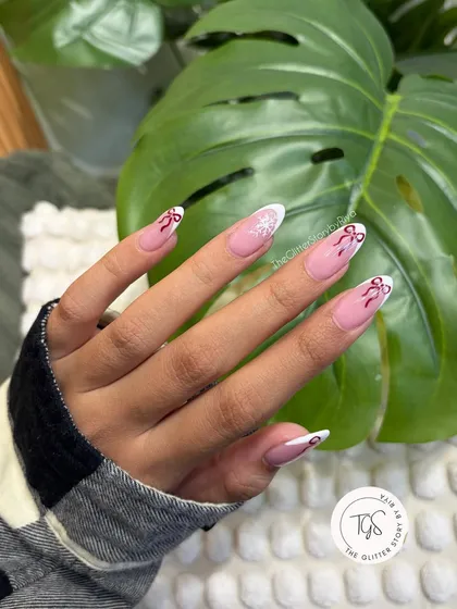 A perfect example of my "not-so-basic" French manicure. This elegant almond-shaped set features a classic white tip, elevated with delicate, hand-painted red bows and a single snowflake accent for a festive touch.