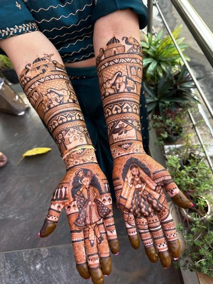 This design showcases a baraat scene on the forearms, with a groom on a horse and a bride in a doli, leading down to couple portraits on the palms.