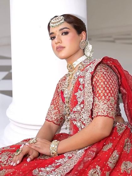 A full seated portrait showcasing the flare of the lehenga and the intricate details of the hand-embroidered work.