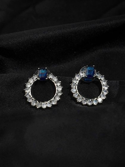 Blue and silver hoop earrings shot against a black background. The high contrast makes the colors and details of the stones pop.
