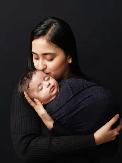 A mother kisses her sleeping newborn's forehead. This is a classic and tender moment that speaks volumes about a mother's love.