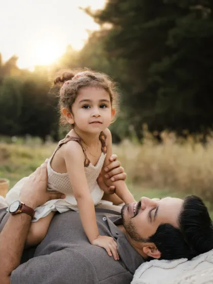 A father and daughter share a quiet moment, lying on a blanket together. This tender portrait showcases their close bond.