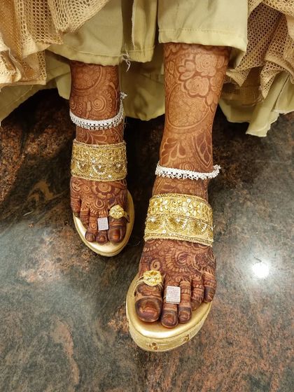 The final look of the bridal feet, adorned with beautiful anklets and toe rings. The dark henna stain provides a stunning backdrop for the jewelry.