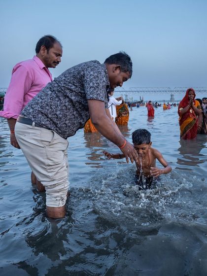 A father guides his young son in the river during Chaiti Chhath Puja, a tender moment of passing down traditions from one generation to the next.