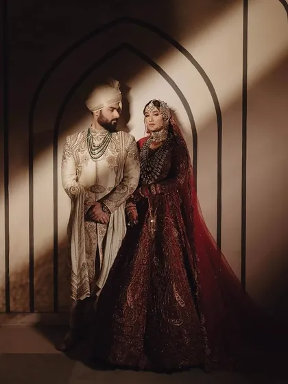 A full portrait of the couple against a dramatic, shadowed archway, creating a timeless and artistic wedding photograph.