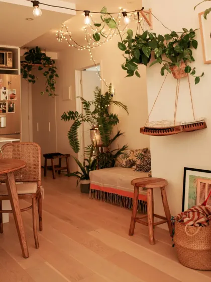 Even a small apartment can feel like a lush retreat. We use a mix of floor plants, hanging vines, and tabletop greenery to maximize the green footprint, turning this living area into a cozy, bohemian jungle.