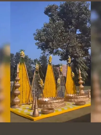A grand outdoor Haldi setup with large triangular structures covered in marigold strings. The golden urlis and props add a royal touch to the entire decor.