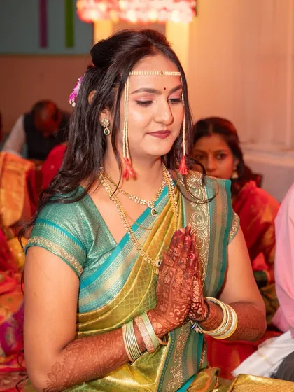 A moment of prayer for engagement bride Ritu. Her traditional Marathi look is complete with a 'mundavalya' (forehead ornament), showcasing an authentic Sakharchpuda style.
