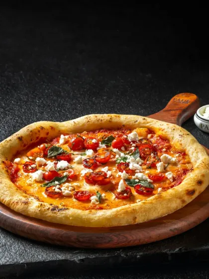 A margherita pizza with cherry tomatoes, fresh basil, and feta cheese, showcasing a fresh and colorful take on a classic.