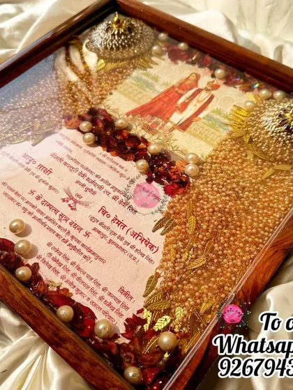 A beautiful frame preserving a wedding invitation, varmala flowers, and kaleera. The golden pearls and intricate details make this a truly luxurious keepsake.