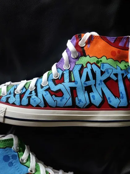 A close-up of the "APARSHAKTI" graffiti art on the custom Converse.