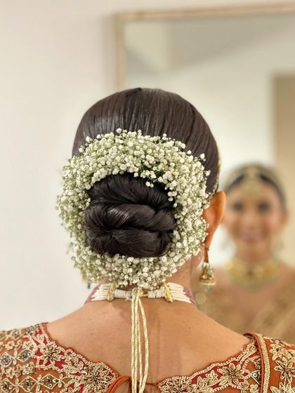 A classic bridal bun adorned with a full gajra of baby's breath, seen from the back.