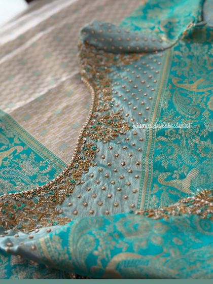 A turquoise blouse with pearl butis and a floral embroidered border.