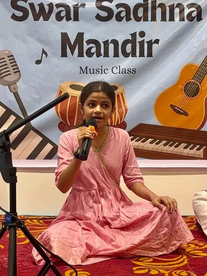 This young performer is confidently singing into the microphone during our Guru Purnima event. We work on everything from sur to stage presence to help our students shine.