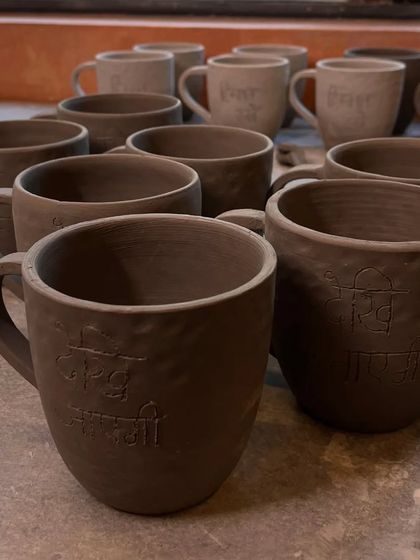 A collection of raw, unfired clay mugs, some with Hindi script pressed into them. This is the stage before the pieces are glazed and fired, where their essential form is born.