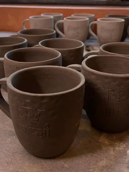 A collection of raw, unfired clay mugs, some with Hindi script pressed into them. This is the stage before the pieces are glazed and fired, where their essential form is born.