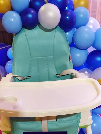 To ensure every detail matches the theme, I can also decorate key areas like the baby's high chair. Here, the chair is surrounded by balloons that match the main stage decor for the first birthday party.