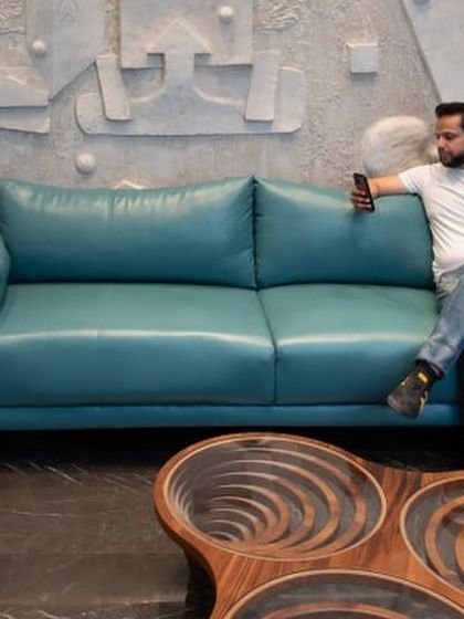 Our principal architect sitting in front of the custom art wall, providing a sense of scale. The sculptural wooden coffee table in the foreground is another example of our focus on unique, artful pieces.