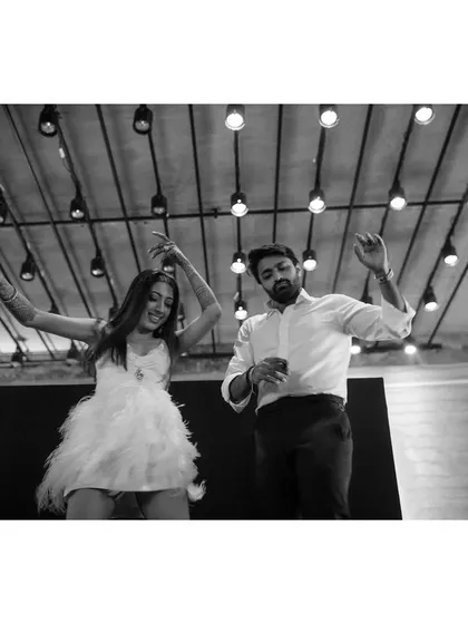 Sanjana and Raghav dance on a light-up floor. This black and white photo from below captures their energy and the fun atmosphere of their engagement party.