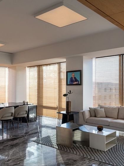 A spacious director's cabin in the Stainless Steel Office, featuring a sculptural stainless steel desk. The room is flooded with natural light from floor-to-ceiling windows, creating a powerful and impressive executive space.