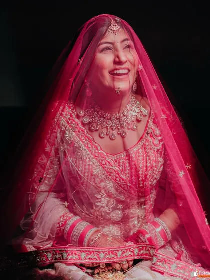 A joyful moment captured under the veil. Mamta's radiant smile shines through, highlighting her beautiful and happy bridal glow.