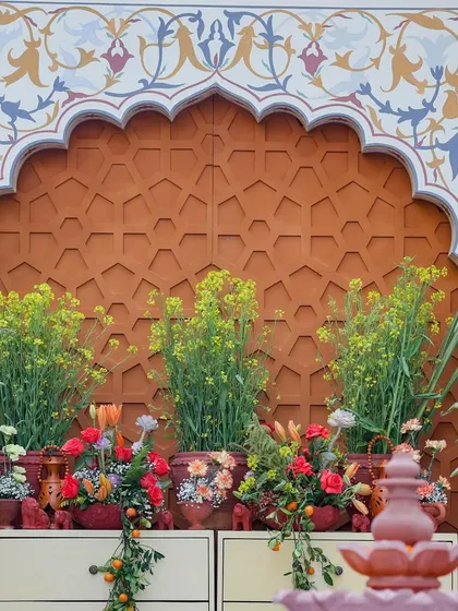 A direct view of the floral arrangement on a console table, showcasing a mix of mustard flowers and colorful blooms against the intricate backdrop.