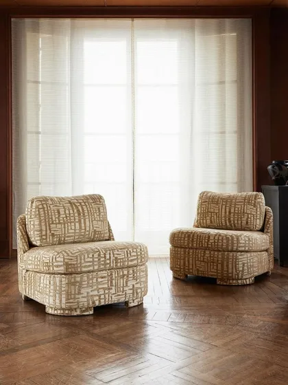 Another view of the 'Montana' slipper chair by Nobilis, highlighting its elegant curves and graceful form. The intricate, patterned upholstery demonstrates how a single piece of furniture can become a room's focal point.