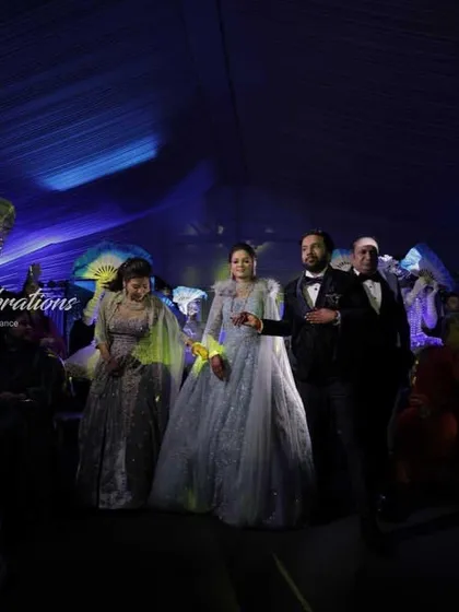 A stylish sangeet entry with performers in sequined silver suits and LED masks. The use of illuminated fans adds another layer of visual interest to this modern and chic couple entrance.