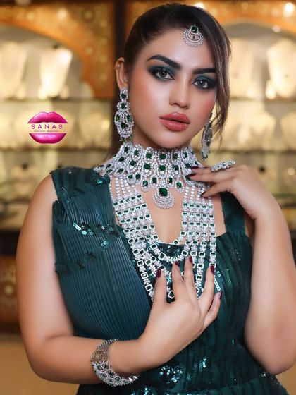 A close-up of the emerald and diamond jewellery set. The makeup was designed to complement the green stones, creating a cohesive and luxurious look.