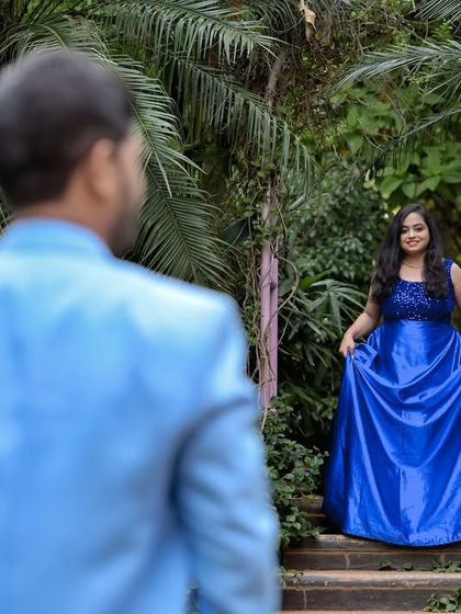 A candid-style shot of a couple on a garden staircase, surrounded by tropical plants.