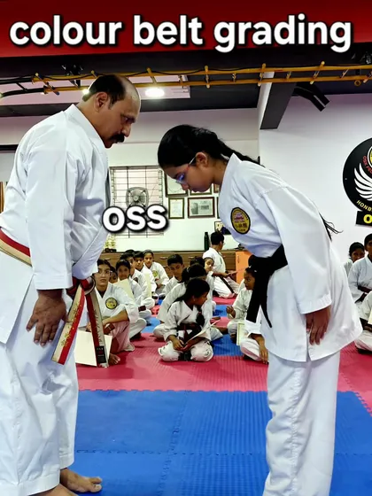 A student shows respect with a bow ('oss') during her colour belt grading. This moment captures the mutual respect between instructor and student that is central to the grading process.