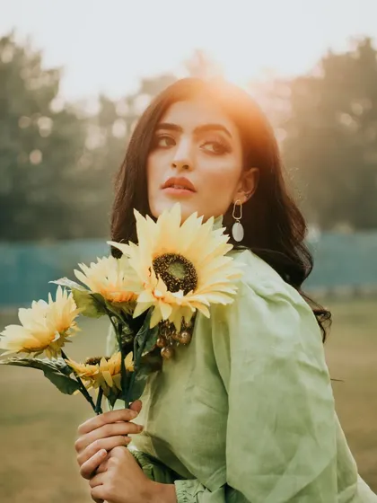Capturing the soft, warm glow of the golden hour. This natural light portrait uses the setting sun as a beautiful backlight, creating a dreamy, story-driven image with a vintage feel in an open park setting.