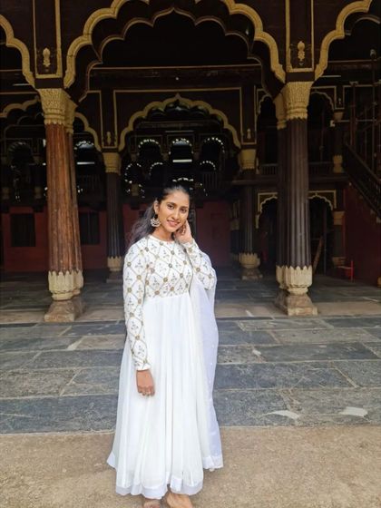 The client wearing her white embroidered Anarkali at a heritage site, showing how the timeless design complements a beautiful backdrop.