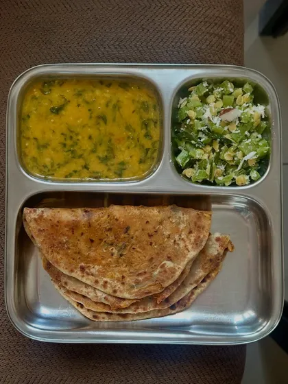 A stuffed paratha served with dal methi and beans palya. This is a filling and nutritious meal, perfect for a busy day.
