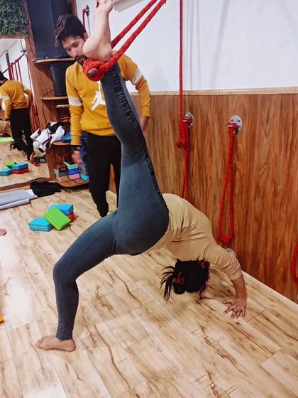 With my guidance, this student is exploring a one-legged wheel pose variation while supported by the ropes, demonstrating incredible focus and control.
