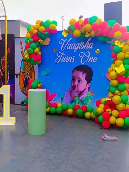 A vibrant first birthday backdrop with a custom photo of the child, framed by a colorful balloon arch.