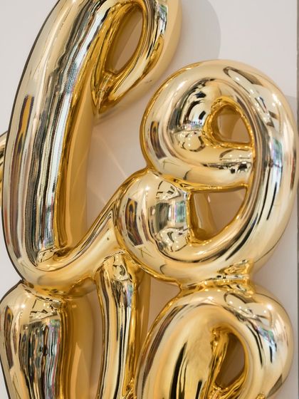 The golden "Love Drip" sculpture represents love as a fluid, ever-flowing emotion. The dripping effect reflects love’s dynamic, sometimes messy nature, flowing freely and taking its own shape.