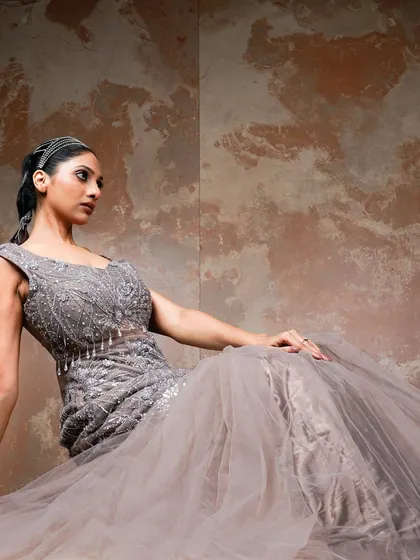 A seated portrait that offers a different perspective on the grey embroidered gown. This pose allows for a closer look at the detailed bodice and the soft tulle of the skirt, conveying a sense of relaxed glamour.