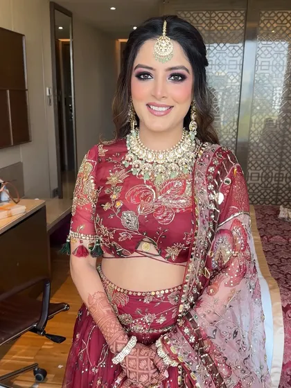 A portrait of the bride, her unique hairstyle adding a playful touch to her traditional red lehenga.